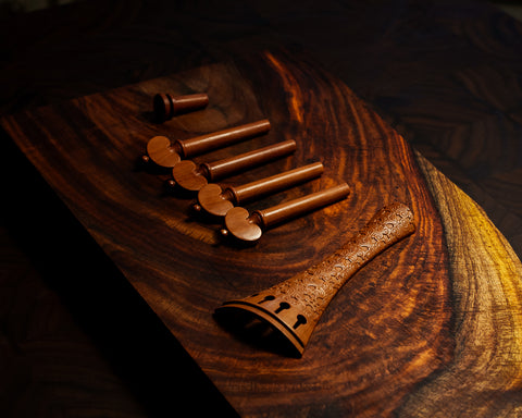A set of violin fittings, including a tailpiece, pegs, and endpin.